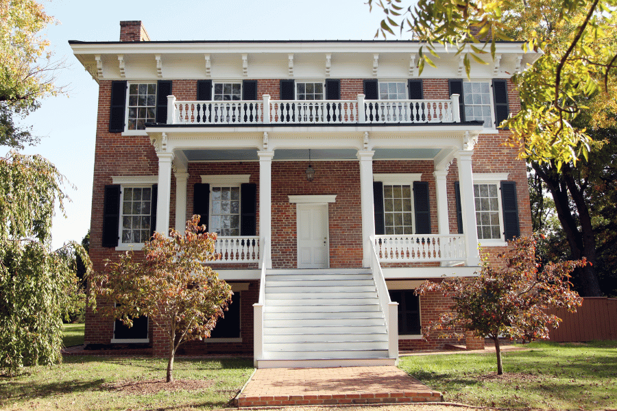 Brick Colonial Revival Home Style with white front porch and black shutters