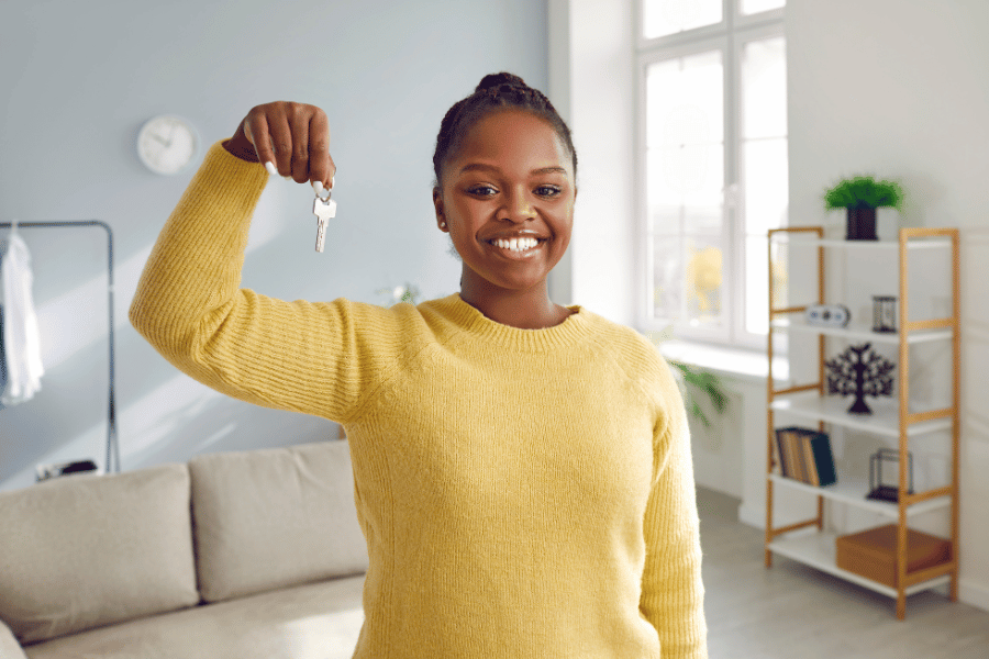 young homeowner with yellow sweater holding up house keys