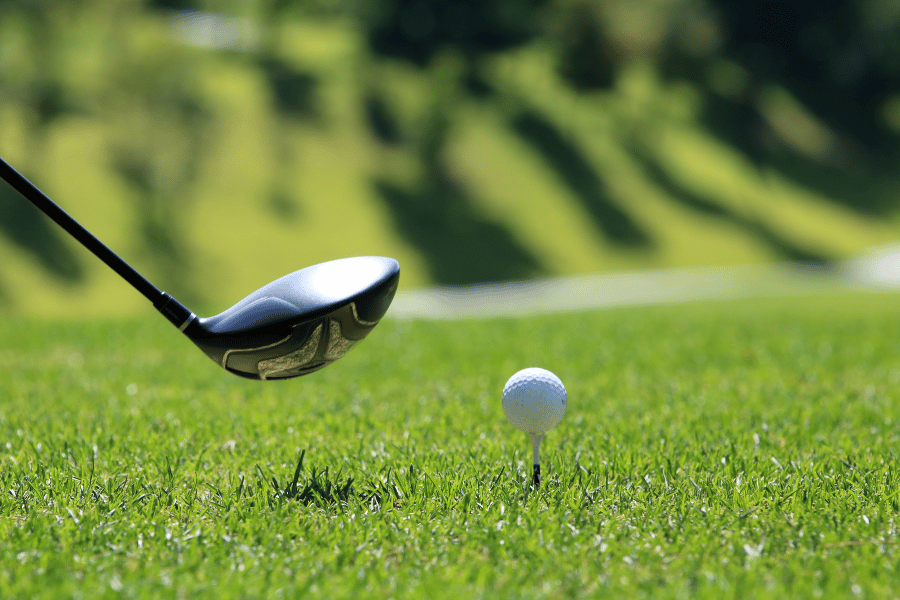 Golf club lining up with golf ball on a green 