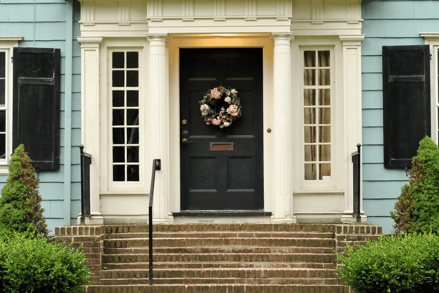 Black front door of Colonial Style Home with brick steps