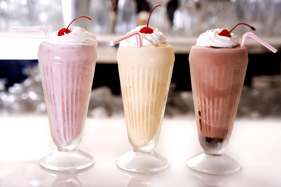 Three milkshakes with whipped cream and a cherry