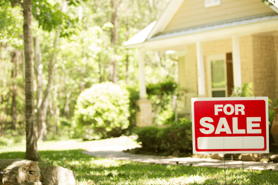 For sale sign in front of a beautiful home in a mature neighborhood