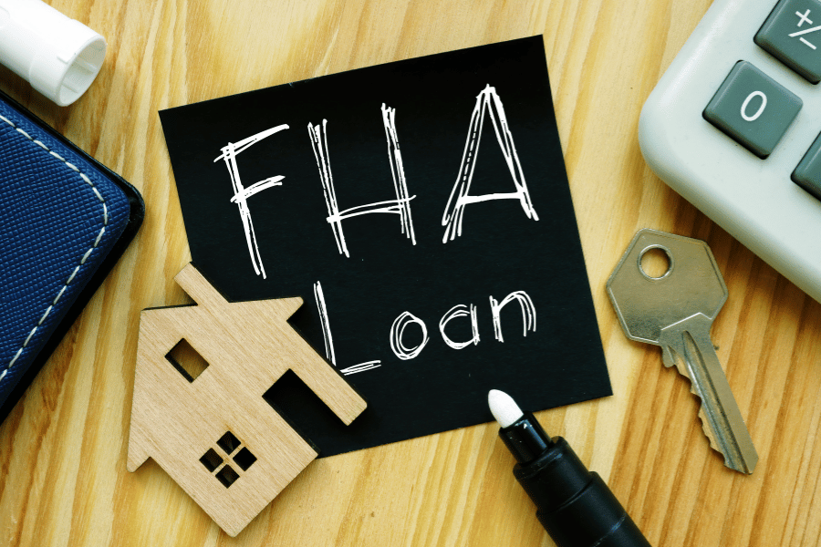 FHA Loan on sticky note with key, pen, and other office supplies
