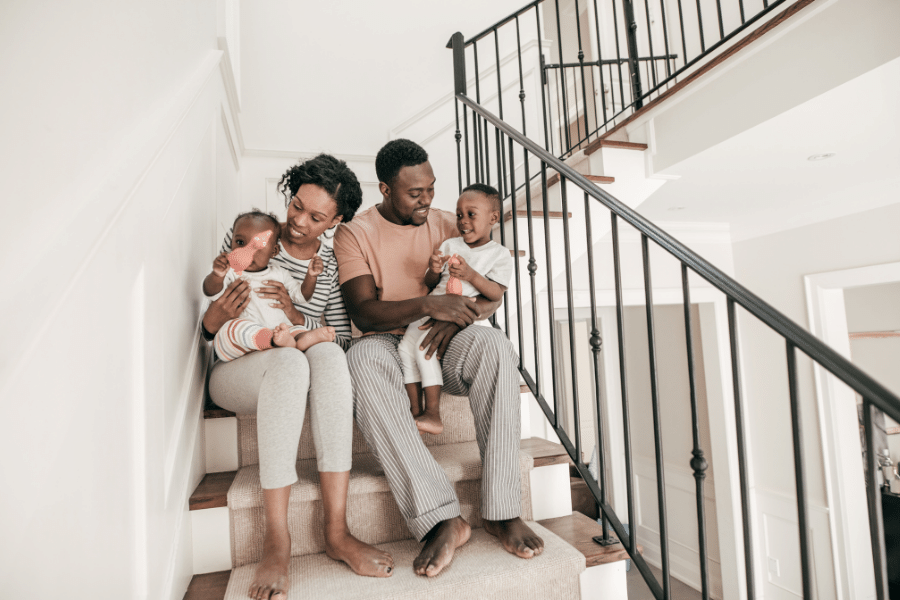 family with children in new home sitting on the stairs
