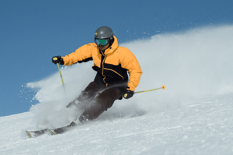 Expert skier perfecting their turns down the mountain wearing a yellow snow suit