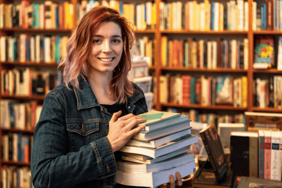 woman buying a stack of books at a bookstore 