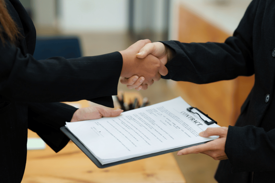 a real estate attorney shaking hands and preparing a contract