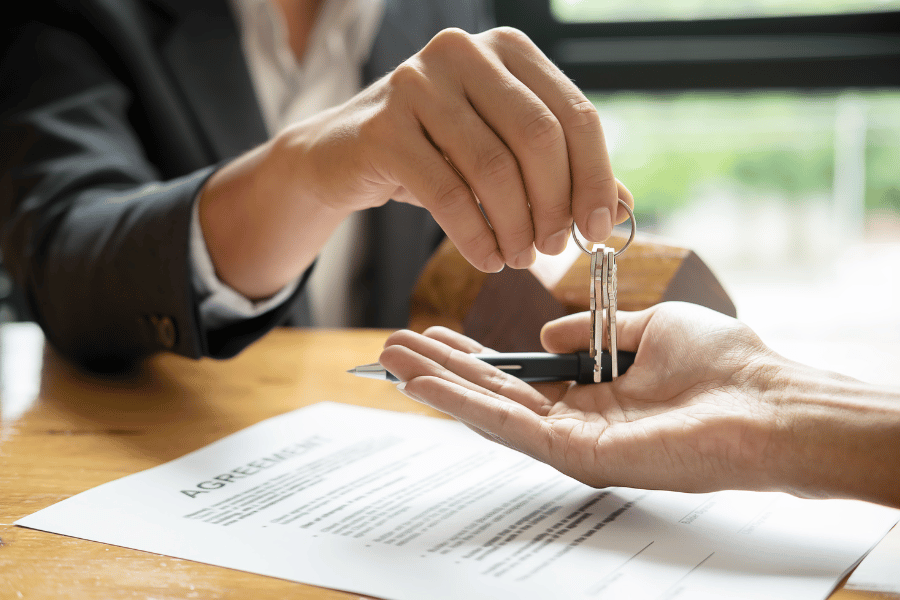 Real estate agent handing keys to home sold over to client 