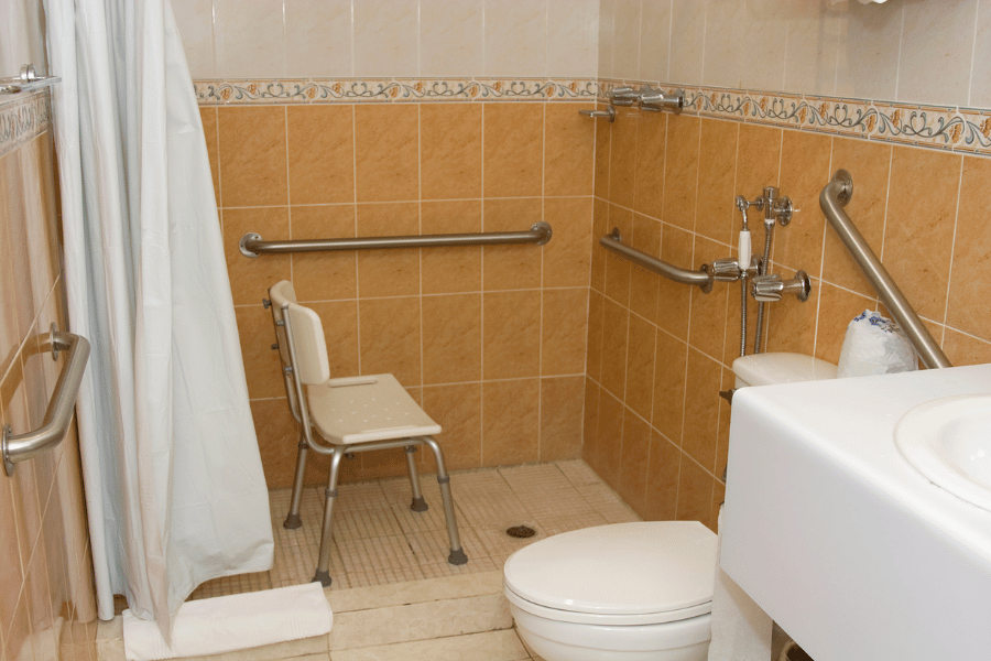 handicap accessible bathroom with chair and grab bars