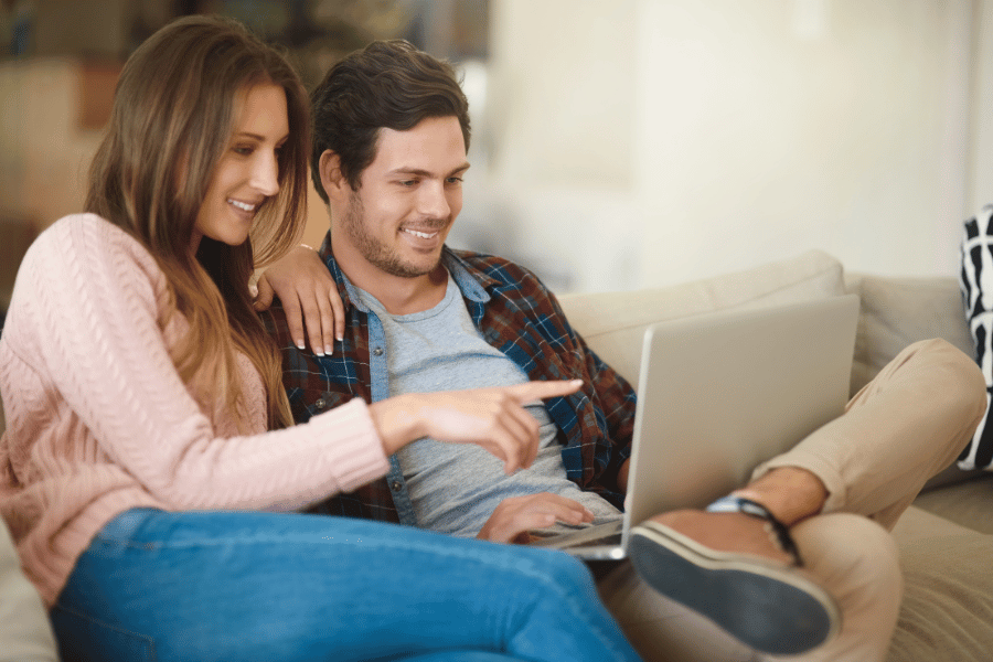 Young couple house hunting online from the couch